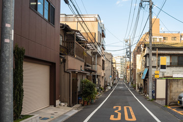 Fototapeta na wymiar Narrow street lined with residential buildings in Tokyo, Japan, on a clear winter day