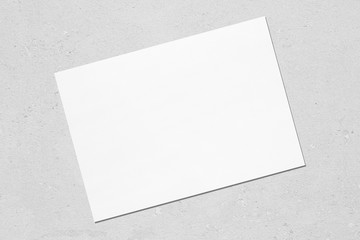 Empty white horizontal rectangle poster mockup with soft shadow lying diagonally on neutral light...