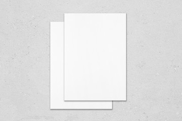 Two empty white rectangle poster mockups lying on top of each other with soft shadows on neutral...