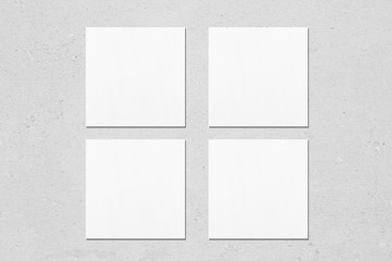 Four empty white square business card mockups with soft shadows on neutral light grey concrete background. Flat lay, top view
