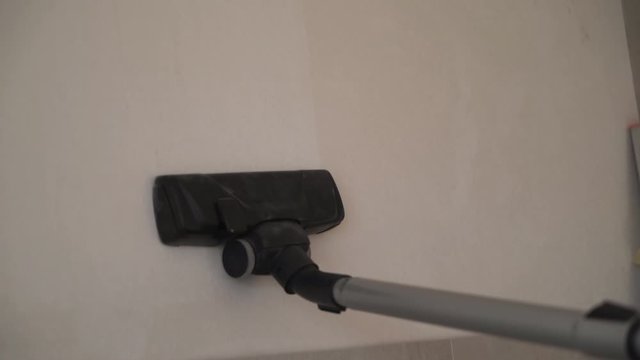 the man is vacuuming the wall. white wall under a thick layer of dust 4K