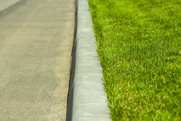 green short-cut grass lawn with a curb near the road