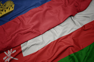 waving colorful flag of oman and national flag of liechtenstein.