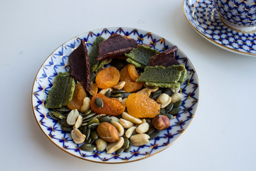 Breakfast of dried fruits walnut and black coffee in a porcelain bowl on a white background