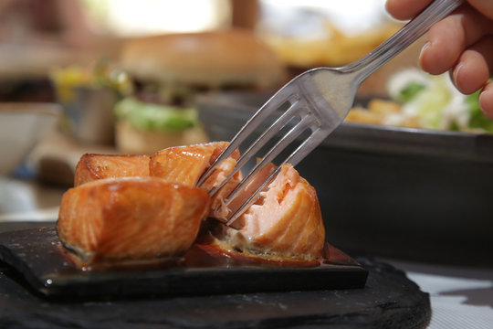 Close up image of a fork and roasted salmon pieces 