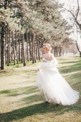 Beautiful blonde bride with stylish make-up in white dress in spring garden 