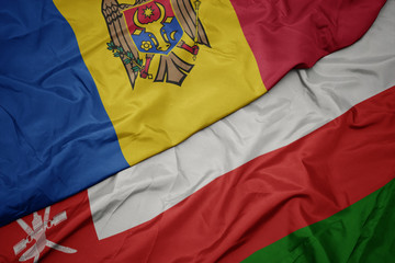 waving colorful flag of oman and national flag of moldova.