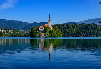 Fototapeta na wymiar Picturesque view of the island on Lake Bled with Pilgrimage Church of the Assumption of Maria with reflection.
