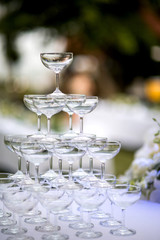 Pyramid of glasses of champagne at outdoor garden in wedding ceremony