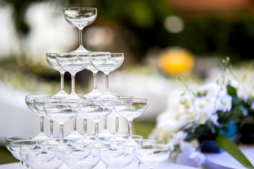 Pyramid of glasses of champagne at outdoor garden in wedding ceremony