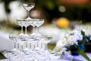 Pyramid of glasses of champagne at outdoor garden in wedding ceremony