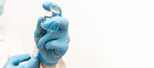 Long wide banner with doctor’s hands in sterile rubber gloves holding vial with vaccine and syringe. Health care concept. Vaccination and flu season concept for medical blog, social media.