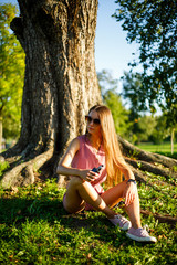 Vape teenager. Young pretty sporty caucasian girl in a pink jumpsuit and sunglasses smoking an...
