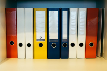 Colorful binders on a shelf with empty labels