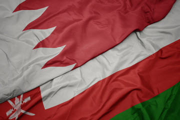 waving colorful flag of oman and national flag of bahrain.