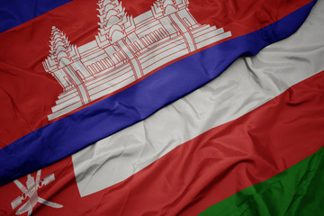 waving colorful flag of oman and national flag of cambodia.