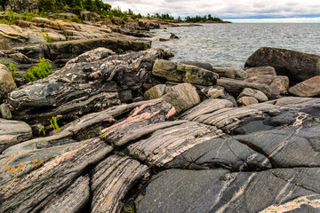 Multibanded gneiss rocks on the shoreline of an island among the 30,000-island archipelago of the...