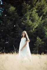 Beautiful girl laughs and dances outdoors in meadow during sunset