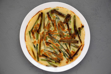 Homemade korean Pajeon scallion pancake on a white plate on a gray background, top view. Asian food.