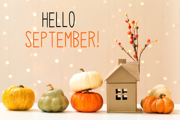 Hello September message with collection of autumn pumpkins with a toy house - obrazy, fototapety, plakaty