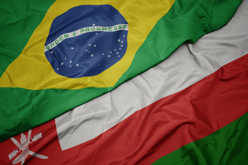 waving colorful flag of oman and national flag of brazil.