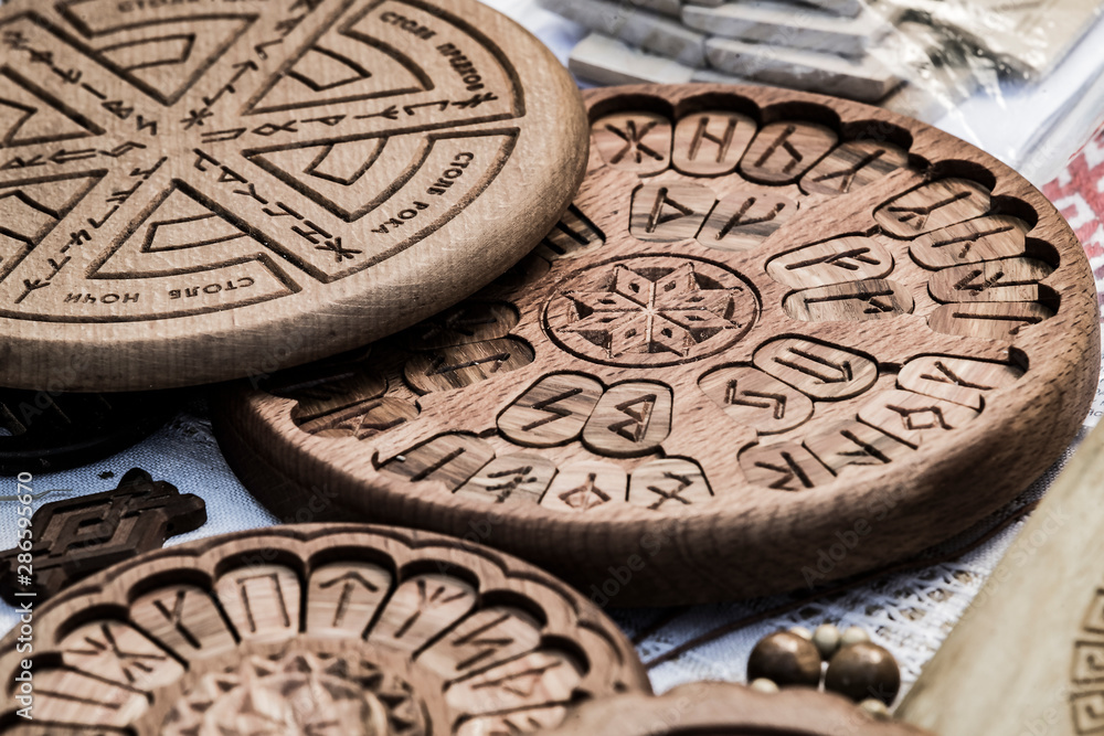 Wall mural Wooden household items with ancient Slavic Nordic handmade symbols crests, runes, hats.