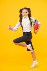 Fototapeta na wymiar An inspirational literature. Adorable little girl running with books of English literature on yellow background. Cute small child enjoy reading childrens literature. Preparing for a literature exam
