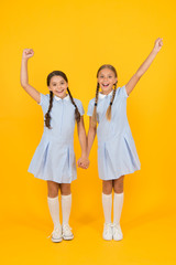 Obraz premium Beautiful schoolgirls. Back to school concept. Hairdresser salon. Cute schoolgirls. Girls with braided hair style. Cheerful schoolgirls yellow background. Little girls playing with cute braids