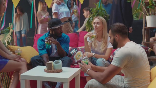Hapy multiethnic young friends drinking alcohol cocktails and having fun together at modern outdoor party in the city.