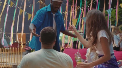 Happy friends party. Black stylish guy hugging his friends girls cheering them up joining the party. Meet up. Summer weekend.