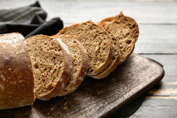 Tasty cut bread on wooden board, closeup