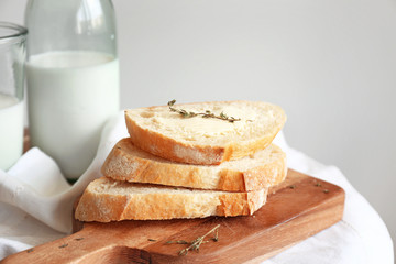Slices of fresh bread with butter, herbs and milk on table
