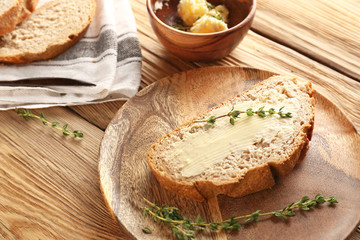 Slice of fresh bread with butter and herbs on wooden table