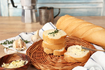 Slices of fresh bread with butter, herbs and garlic on table