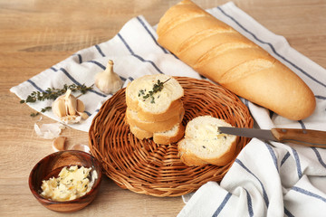 Slices of fresh bread with butter, herbs and garlic on table