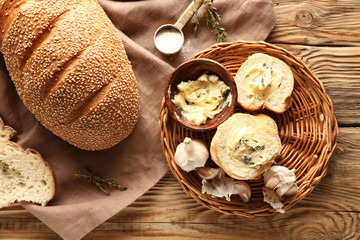 Slices of fresh bread with butter, herbs and garlic on table
