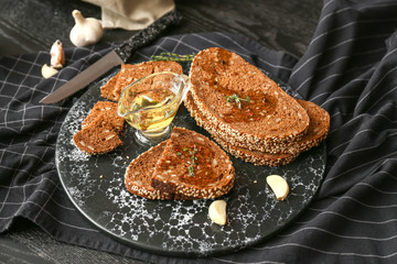 Board with slices of fresh bread, oil and spices on table