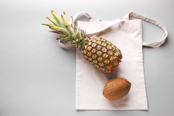 Eco bag with pineapple and coconut on grey background
