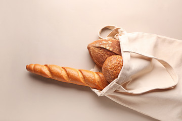 Eco bag with fresh bread on grey background