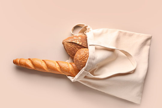 Eco bag with fresh bread on grey background