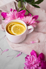 Fototapeta na wymiar View of warm cup of lemon tea with pink flowers