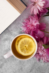 Top view of cup of lemon tea,book and pink flowers