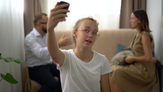 teenage girl taking selfie with quarreling parents sitting on couch family drama