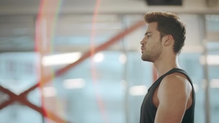 Strong guy lifting dumbbells in sport club. Tired sport man training muscles.