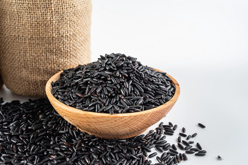 Sacks filled with grain and a bowl of black rice on a white background