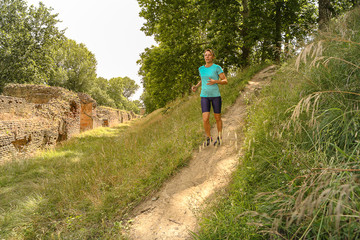 caucasian woman with Sporty body running at the park, on downhill in the countryside between the trees and beautiful nature