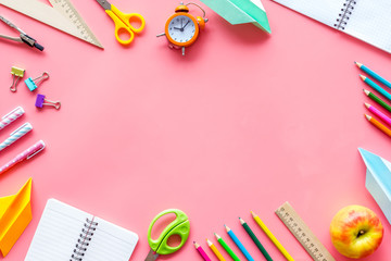 Student accessories frame on pupil's desk pink background top view mockup