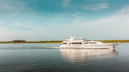 Fototapeta na wymiar Luxury yacht travels in the Indian River headed to open ocean in New Smyrna Beach, Florida