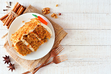 Slice of homemade carrot cake with cream cheese frosting. Above view over a rustic white wood...