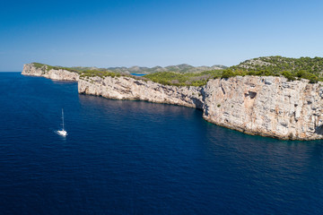 Yacht sailing on the Adriatic sea, cliffs of National park Telascica in background, Croatia